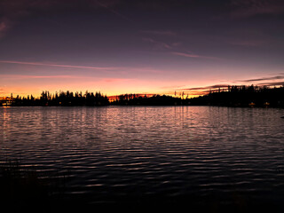 The bright crimson sun, which finds its continuation beyond the lake horizon