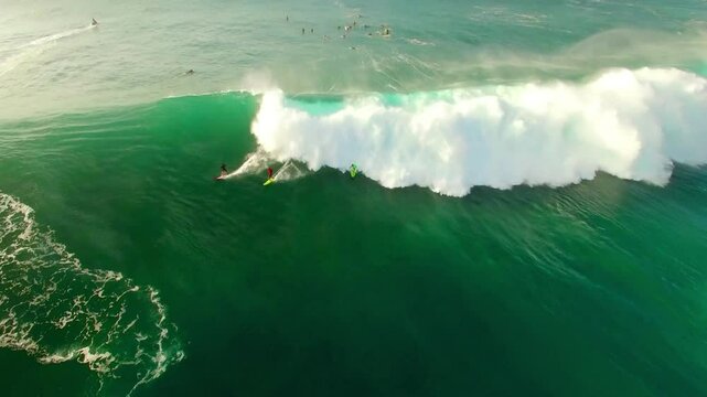 Aerial Backward Shot Of Surfers Surfboarding On Turquoise Wavy Sea During Vacation - Oahu, Hawaii