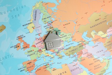 Metal house model on world map, above view. Accommodation search
