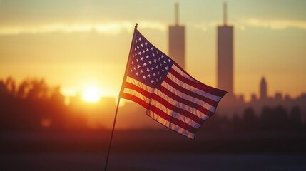 American flag waves gently at sunrise reflecting 911 tribute. Silhouette of Twin Towers. Morning light evokes solemn remembrance, hope. Scene is emotional, iconic. Photo captures historical moment.