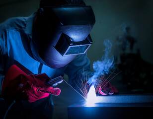 A worker manually welds steel and stainless steel components using TIG technology, detail of an electric arc.	