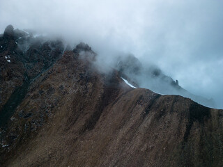 Stunning summer view of the mountains of Kyrgyzstan, clouds sliding over rocky peaks - the calm beauty of nature.