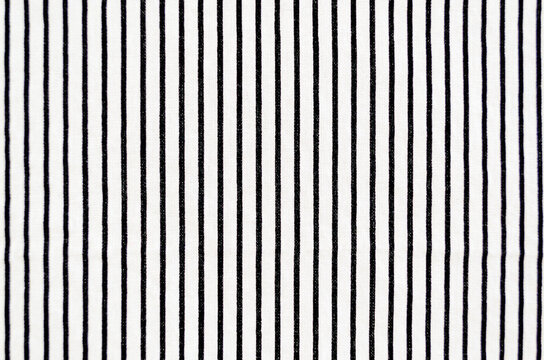 Close-up of whte fabric with vertical black stripes filling the frame.