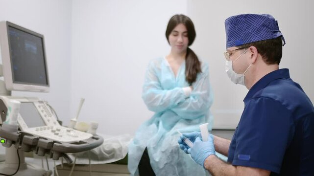 Mammalogist doctor is preparing to examine woman breasts and lymph nodes using ultrasound for diagnosis of breast cancer during appointment. Oncologist holding hands biopsy slide glasses and syringe.