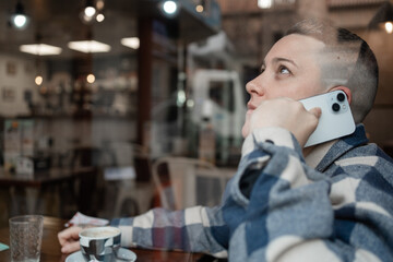 Woman with short hair making a phone call in a cafe