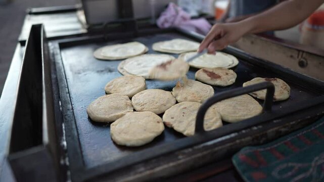 In a bustling street market in Granada, vendors prepare fresh pupusas and quesillo on a hot griddle, showcasing the delightful street food culture of Nicaragua.