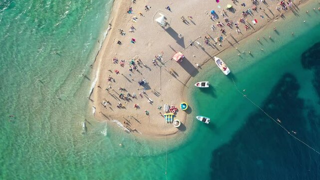 Zlatni Rat, Bol, Croatia - Beach Tip with Boats and Waves. Zlatni Rat beach in Bol, Croatia. The video captures the vibrant scene with sun umbrellas, boats, turquoise waters. Iconic Adriatic beach.