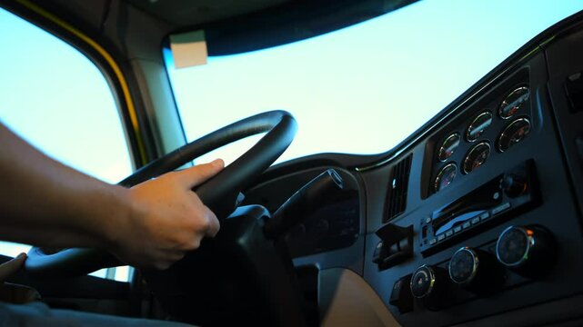 Professional Truck Driver are holding steering wheel while driving. Bottom up view of truck dashboard. Shot from inside the truck.