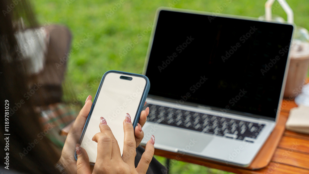 Wall mural close up of freelancer using mobile phone and laptop with empty white screen on sunny day