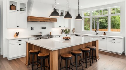 Bright kitchen interior featuring an island with seating, complemented by a panoramic window offering views of the countryside.