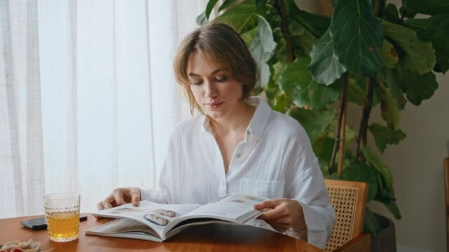 Domestic girl looking magazine article at home breakfast closeup. Woman morning