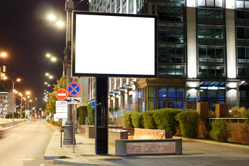 Large horizontal billboard in the night city. Building with multi-level parking, clean road. Mock-up.