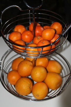 Two tier metal fruit baskets filled with  fresh oranges 