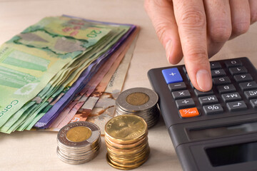 Closeup person's hand using calculator counting canadian cash money
