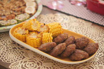 Indulge in a Delightful Platter Featuring Grilled Corn and Savory Meat Patties