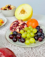 Fruchtiger Obstsalat mit tropischen Früchten Melone Apfel Birne Weintrauben Banane Granatapfel Orange Mandarine