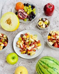 Fruchtiger Obstsalat mit tropischen Früchten Melone Apfel Birne Weintrauben Banane Granatapfel Orange Mandarine