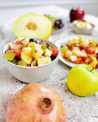 Fruchtiger Obstsalat mit tropischen Früchten Melone Apfel Birne Weintrauben Banane Granatapfel Orange Mandarine