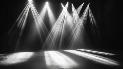 Black-and-white photography of an empty stage with spotlights shining down, creating beautiful light rays on the floor