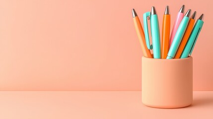 Fototapeta premium A vibrant collection of colorful pens arranged in a peach-colored holder against a soft peach background.