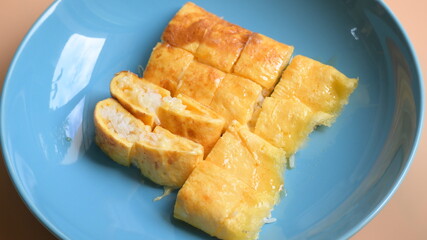 roll omelette stuffed with chesse and rice on blue plate, delicious food in the morning