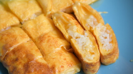 roll omelette stuffed with chesse and rice on blue plate, delicious food in the morning