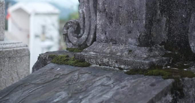 A hand rests on a gravestone with anger.