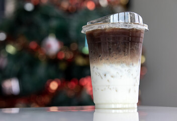 Iced coffee in a plastic cup  Separate layers of coffee and milk placed on a white table.