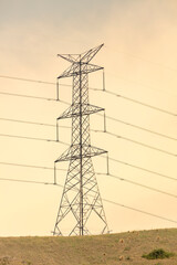 Photograph of a large electricity Transmission Tower on a grassy hill against an orange sunset sky in regional Australia.