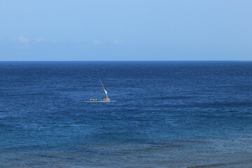 Obraz premium Sailboat Navigates Calm Blue Ocean with Clear Sky on a Tranquil Day