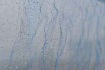 Raindrops on Blue Mesh with a Soft Background