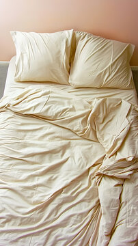 Serene unmade bed with soft beige linens.
