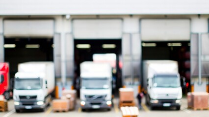 Factory Transport Setup: Blurred view of a warehouse and parked logistics trucks.
