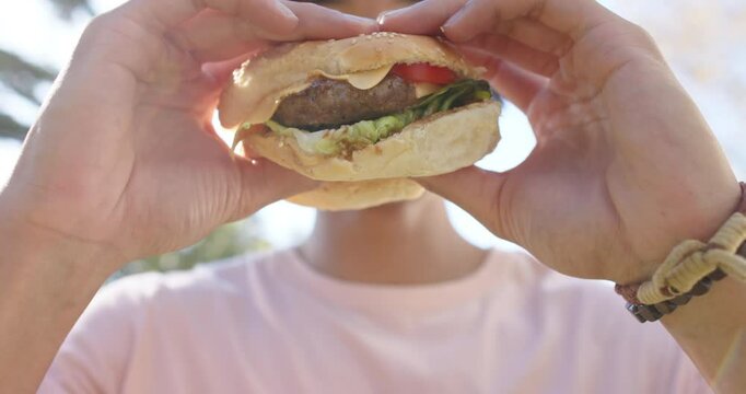 Holding burger, man preparing to take bite during outdoor hangout