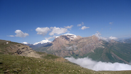 Giant ridge with snow under cloudy sky. Amazing mountain range in overcast weather. Unusual foggy rocks. Wonderful landscape of majestic nature of highlands. Caucasus Mountains, Shahdag