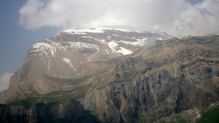 Giant ridge with snow under cloudy sky. Amazing mountain range in overcast weather. Unusual foggy rocks. Wonderful landscape of majestic nature of highlands. Caucasus Mountains, Shahdag