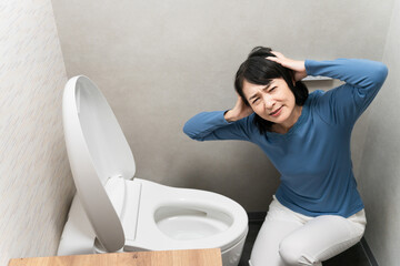 トイレのトラブルで困るミドル女性　ライフスタイルイメージ
