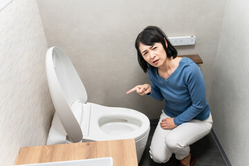 トイレのトラブルで困るミドル女性　ライフスタイルイメージ