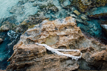 Vieille corde abandonnée sur des rochers de la côte méditerranéenne. Pollution de la mer. Roche, eau bleue et corde blanche