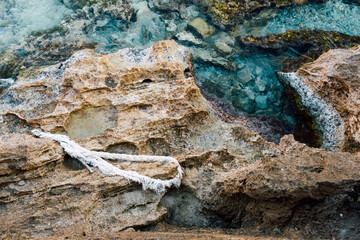 Vieille corde abandonnée sur des rochers de la côte méditerranéenne. Pollution de la mer. Roche, eau bleue et corde blanche
