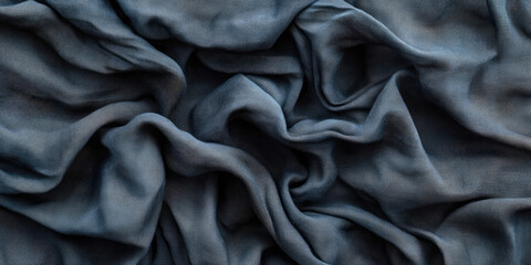 Fototapeta premium The image shows a close-up of a dark, textured fabric with deep folds and wrinkles