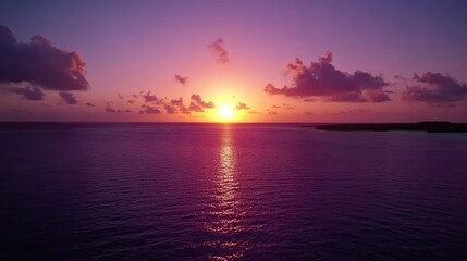 Fototapeta premium Stunning sunset colors illuminating the sky with rich purples and reds, reflecting off the calm ocean and blending with the horizon.