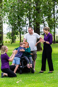 Boy and parents chatting with occupational therapist and speech pathologist outdoors