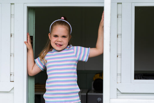 Little girl standing in play cubby house on farm with lymphatic malformation and speech disability