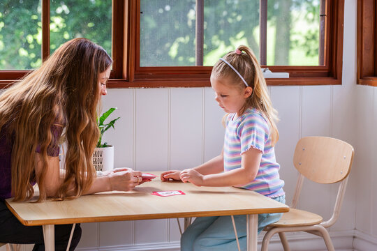 Speech pathologist working with young girl using word flash cards for language development