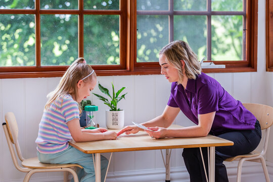 Child with speech disability looking at sound cards talking with speech-language pathologist