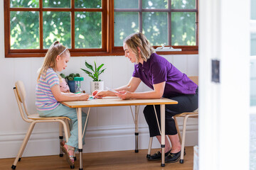 Child sitting at desk in speech pathology clinic using phonics card resources