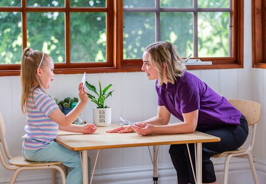 Child with speech disability looking at sound cards talking with speech-language pathologist