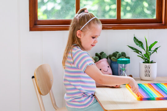 Child sitting at desk in speech pathology clinic concentrating on rainbow poppet toy