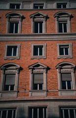 A beautiful red brick building with grey stone window frames, showcasing a perfect blend of classic architecture and rustic charm. A timeless piece of craftsmanship in the heart of the city.